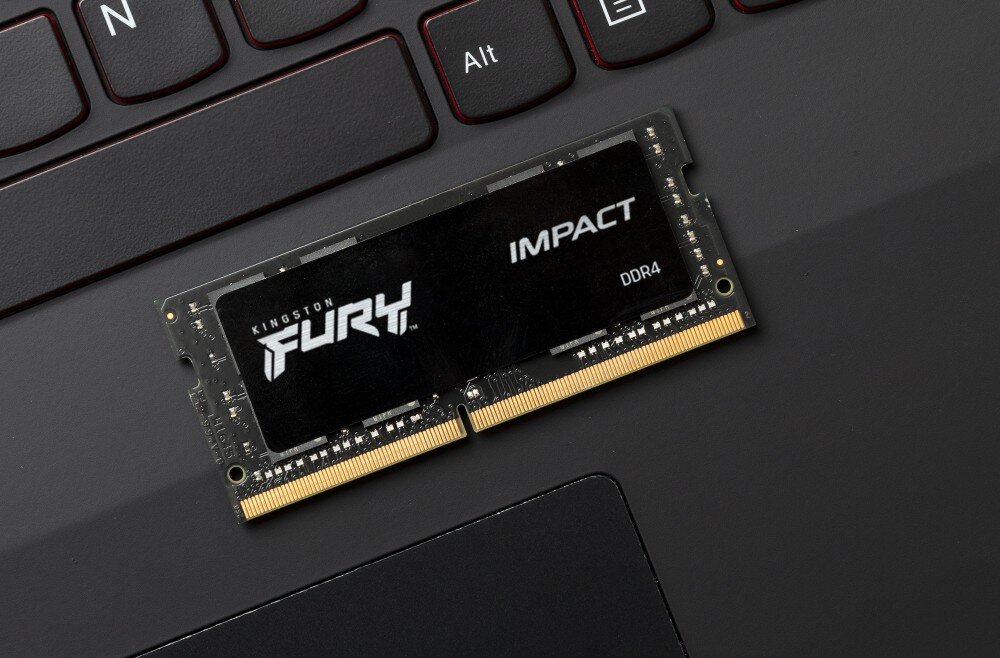 Pamięć RAM KINGSTON Fury Impact 32GB 3200MHz Czarny moduł pamięci z napisem 'FURY' i 'IMPACT DDR4' leżący na klawiaturze laptopa w pobliżu klawiszy 'Alt' i 'N', wygląd, konstrukcja