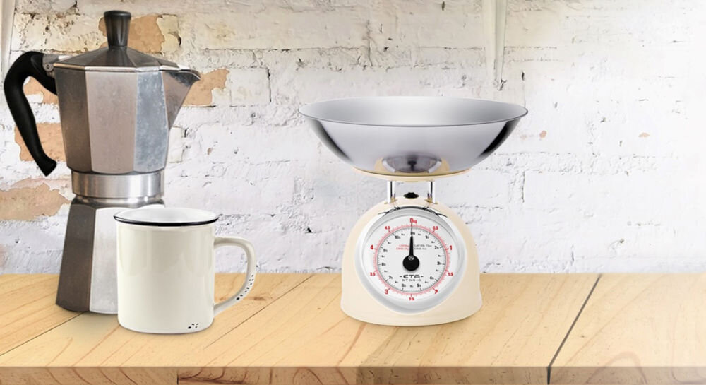 Waga kuchenna ETA Storio 577790040 beżowa waga dużyw skaźnik srebrna misa obok stoi kawiarka do ważenia składników aż do 5 kg precyzja do 25 g funkcja zmiany jednostek gramy kilogramy funty uncje funkcjonalność kreatywność dokładność 