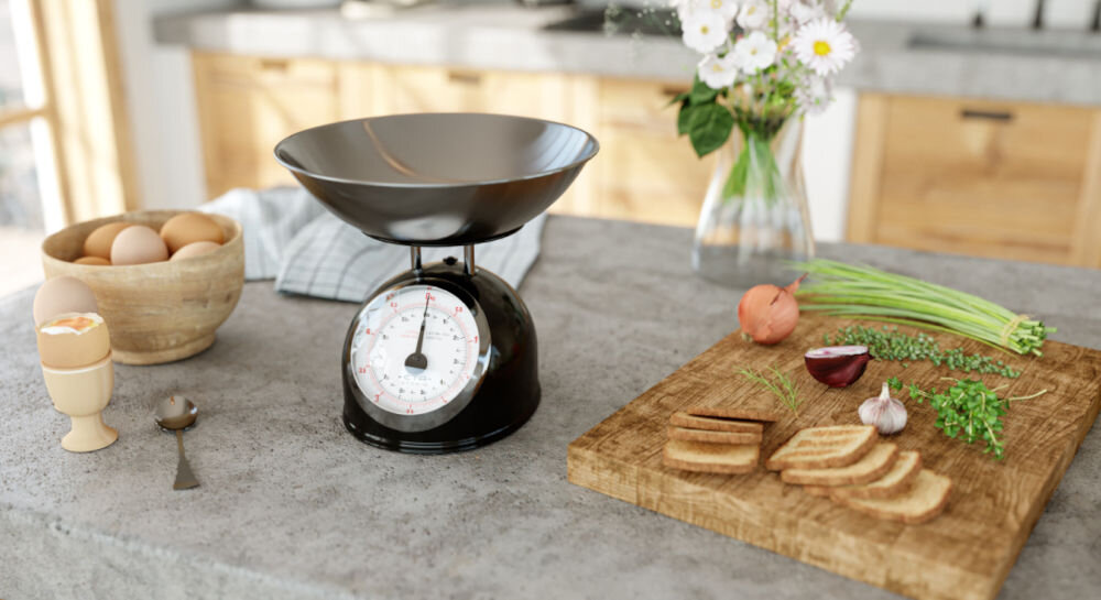 Waga kuchenna ETA Storio 577790020 precyzyjne ważenie czarna waga stoi na blacie srebrna miska duży wskaźnik obok składniki na desce  