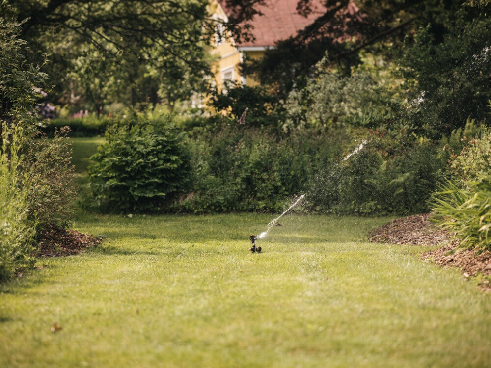 Zraszacz FISKARS 1027050, zawór, on off, wygoda, sucha odzież, w tle ogród, zraszacz z daleka podlewa duży obszar działki
