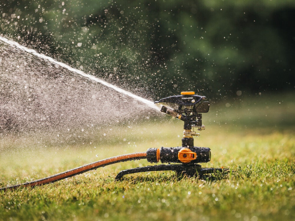 Zraszacz FISKARS 1027050, metal, trójnóg, stabilność, mgiełka, zbliżenie na zraszacz podlewający trawnik