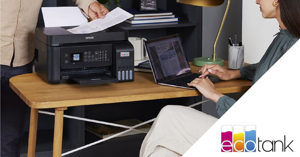 Urządzenie wielofunkcyjne EPSON EcoTank L5290 Druk w kolorze, Wi-Fi prezentacja urządzenia na biurku przy biurku siedzi kobieta z laptopem a do urządzenia mężczyzna wkłada kartkę bezkartridżowa oszczędność kosztów