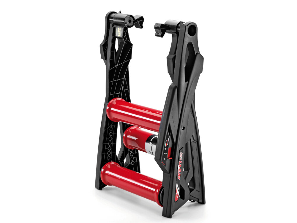Trenażer rowerowy ELITE Arion Mag złożony trenażer na białym tle waga 7,8 kg uchwyty w pobliżu zawiasów łatwo przenosić i przechowywać składana konstrukcja złożenie jednym ruchem zintegrowany stopień ułatwia wsiadanie i zsiadanie