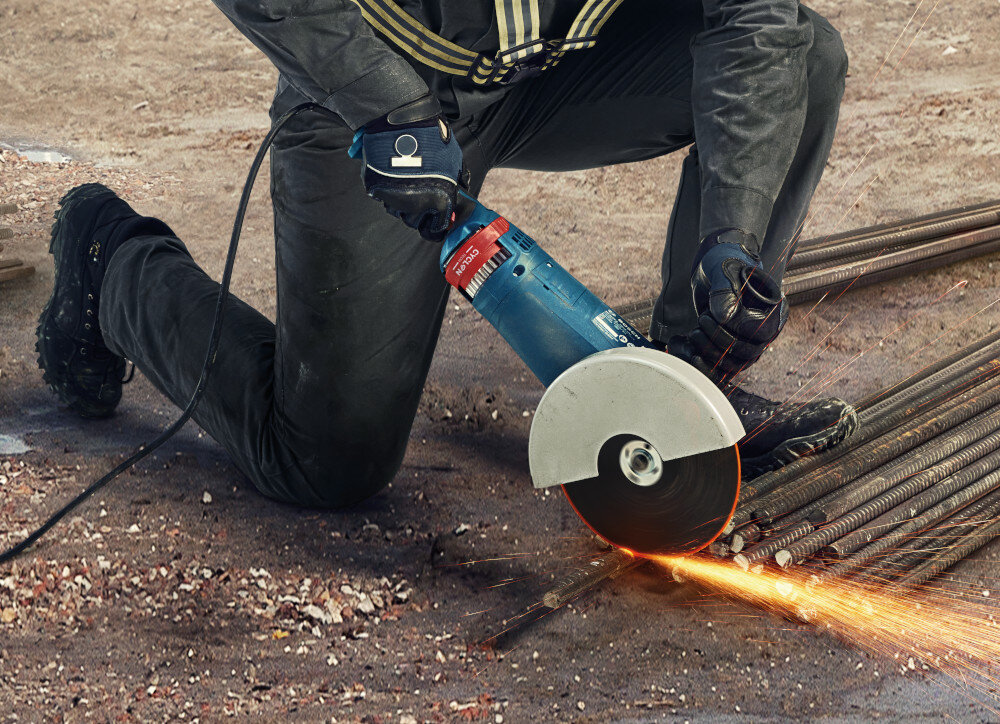 Szlifierka kątowa BOSCH GWS 24-230 JZ osoba trzyma szlifierkę w dłoniach tnąc metalową rurkę ergonomiczna konstrukcja rękojeści wygodna obsługa ergonomiczna rączka o bardzo małym obwodzie miękka powłoka typu SoftGrip stabilny chwyt