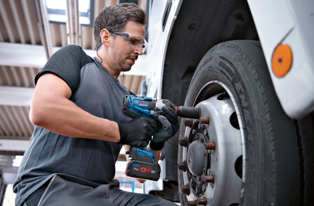 Klucz udarowy BOSCH Professional GDS 18V-1000 06019J8300 warsztat samochodowy osoba dokręca śruby w kole do profesjonalnych zastosowań szybkość i wygoda pracy ułatwia dokręcanie i odkręcanie śrub od metalu do drewna w domu przy pracach wymagających solidnego dokręcenia śrub mechanizm udarowy wysoka siła