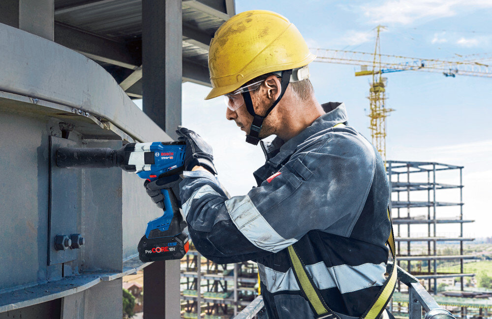 Klucz udarowy BOSCH Professional GDS 18V-1000 06019J8300 metalowa konstrukcja osoba dokręca śrubę na konstrukcji w tle dźwig rusztowania niebo szereg zabezpieczeń elektroniczna ochrona ogniw ECP system ochrony silnika EMP monitorują temperaturę i obciążenie podzespołów zmniejsza się ryzyko przegrzania, przeciążenia i skrócenia żywotności baterii większe bezpieczeństwo użytkownika dłuższe użytkowanie sprzętu