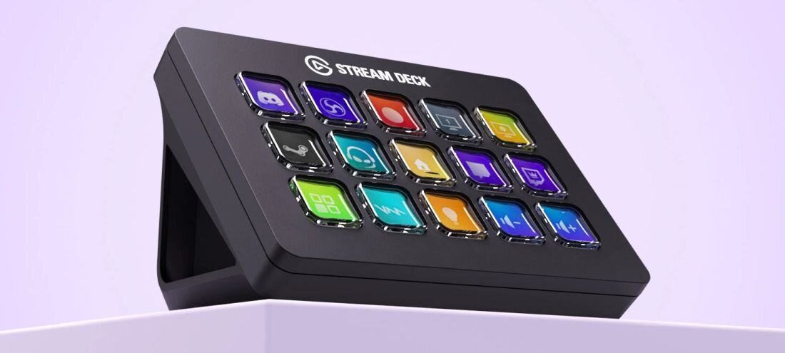 Panel Elgato Stream Deck stoi na podniesionej powierzchni, prezentując piętnaście kolorowych przycisków na jasnym fioletowym tle - Regulowana podstawka w zestawie  