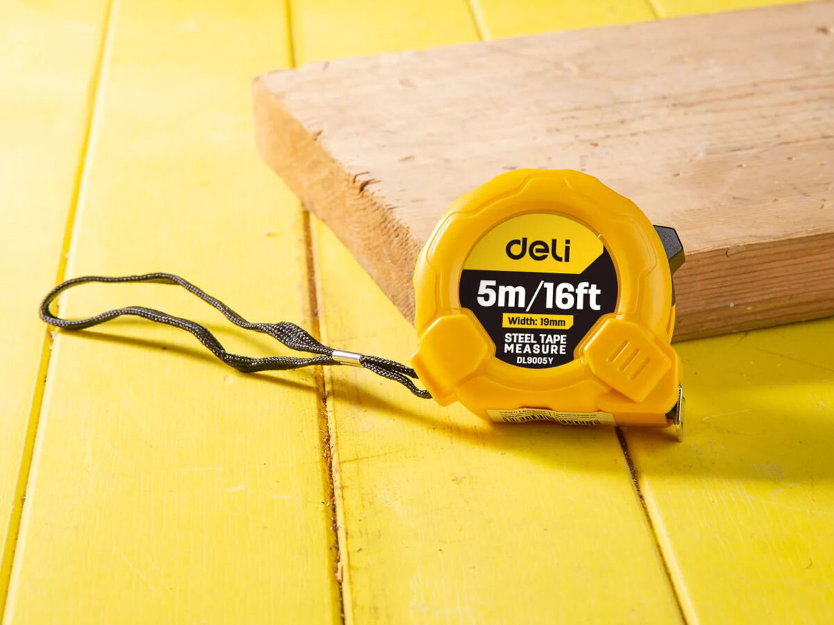 Miara zwijana DELI TOOLS EDL9005Y (5 m), mierzenie, pomiar, wygoda, praca, miara opiera się o deskę na żółtej drewnianej podłodze