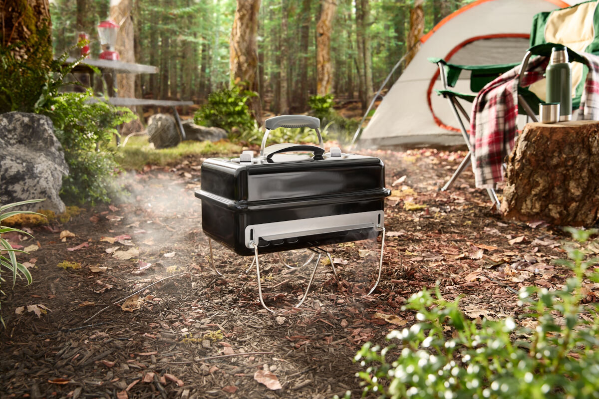 Grill węglowy WEBER Go-Anywhere 1131004, mobilność, grill, podróż, kemping, Przenośny grill Weber w użyciu na kempingu w lesie obok namiotu.