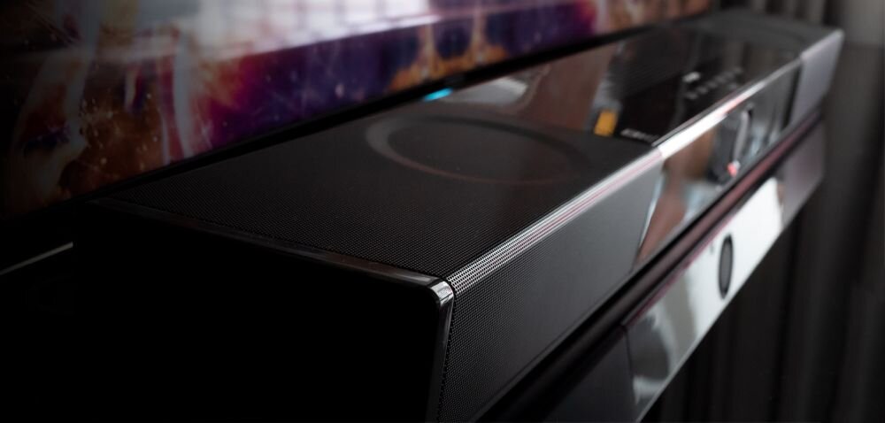 Soundbar komputerowy CREATIVE SXFI Carrier dźwięk Dolby Atmos kino domowe przestrzeń audio, soundbar pod skosem stojacy na czarnym blacie