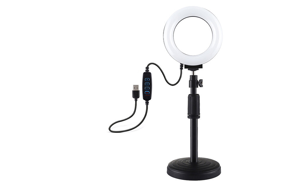 Lampa pierścieniowa LED z regulowaną podstawką, wyposażona w kabel USB z kontrolerem. Lampa ma okrągły kształt i jest zamontowana na czarnej podstawce.