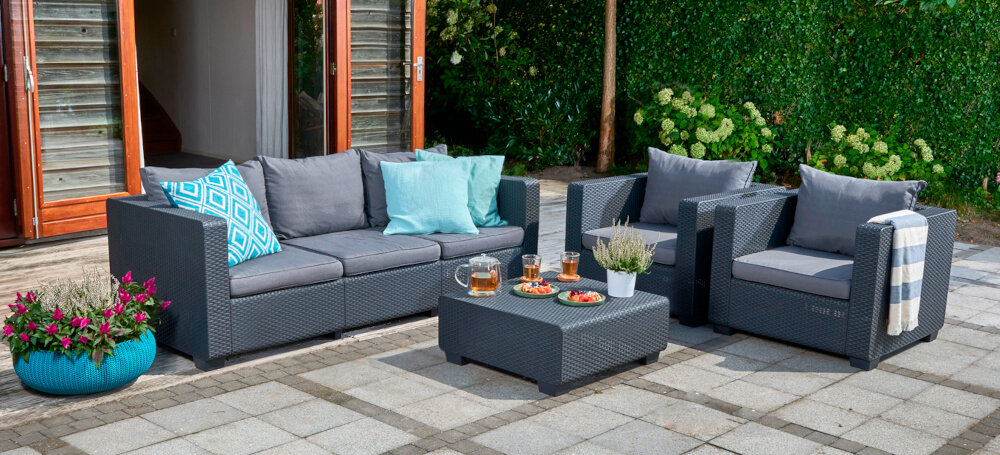 Stolik ogrodowy KETER Salta 17206013 Grafitowy zestaw mebli ogrodowych na tarasie w tle dom i rośliny z wysokiej jakości tworzywa sztucznego nie traci koloru i nie pęka pod wpływem skrajnych temperatur blat odporny na działanie wilgoci zarysowania i wysoką temperaturę nie wymaga dodatkowej pielęgnacji