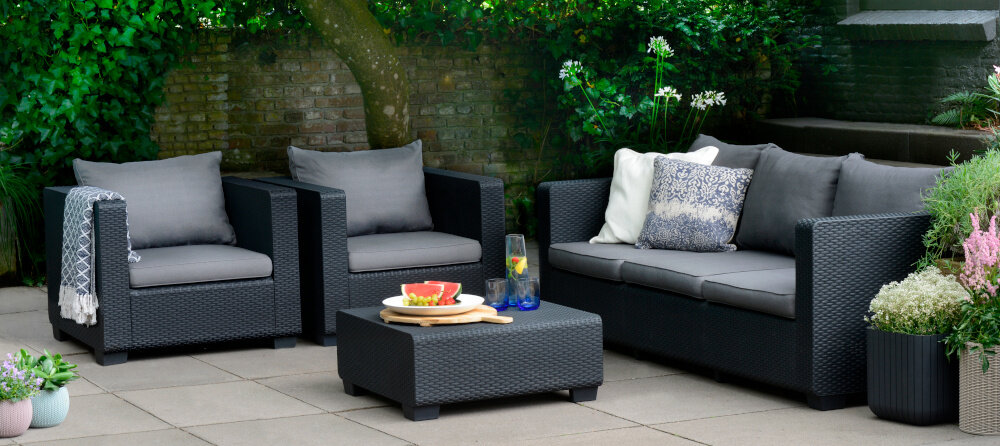 Stolik ogrodowy KETER Salta 17206013 Grafitowy zestaw mebli ogrodowych na tarasie w tle schody i rośliny na stoliku szklanki talerz z owocami imituje naturalny splot rattanowy grafitowa kolorystyka estetyka spójność w przestrzeni ogrodowej