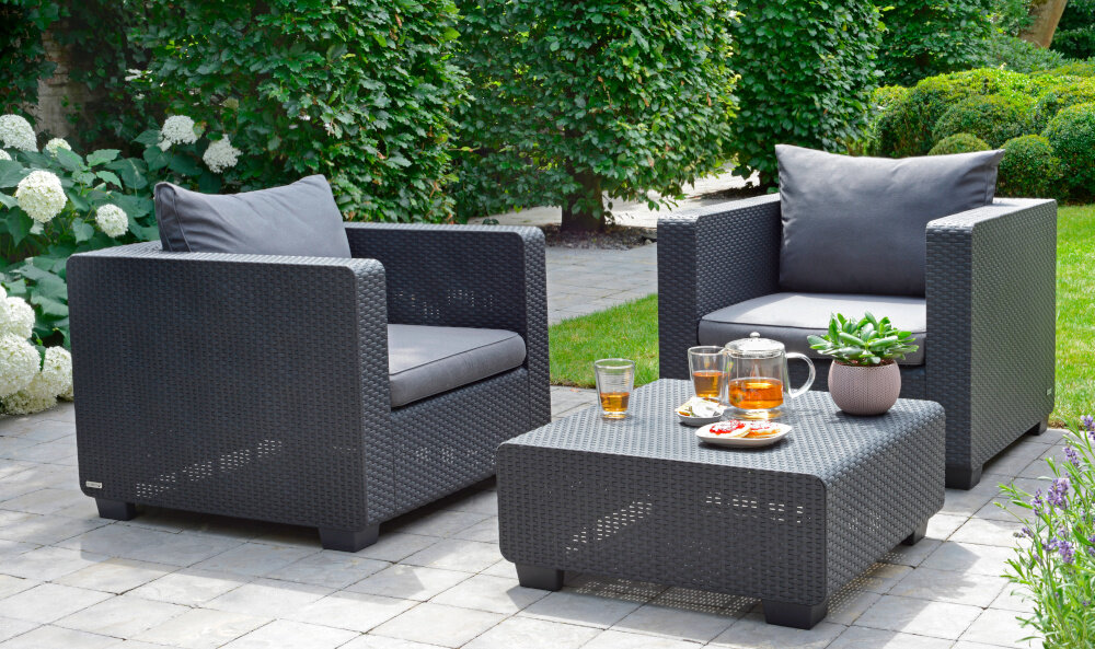 Stolik ogrodowy KETER Salta 17206013 Grafitowy zestaw mebli ogrodowych na tarasie dwa fotele obok stolik na stoliku doniczka dzbanek szklanki i talerz z przekąskami prostokątny blat o wymiarach 71,5 x 71,5 cm wysokość 30 cm współgra z niskimi fotelami czy leżakami brak otworu na parasol nierozkładana forma maksymalny udźwig do 20 kg