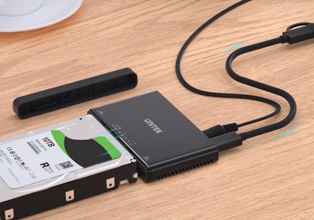 Stacja dokująca UNITEK S1222A Urządzenie podłączone kablami do dysku HDD 10TB oraz komputera na drewnianym blacie