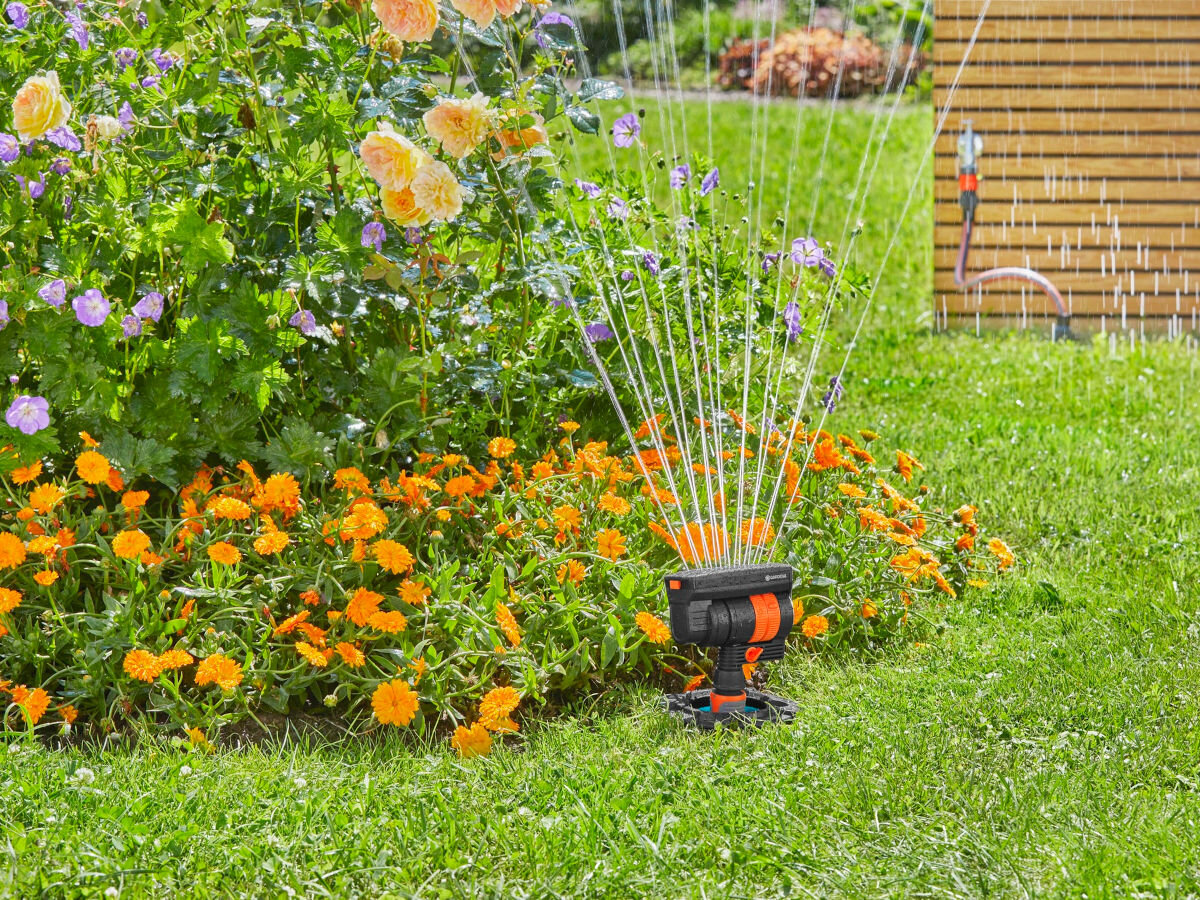 Zestaw startowy GARDENA 8272-20, wygoda, podlewanie, instalacja, woda, w tle ogród i altana, na pierwszym planie zestaw podlewa rabatę ogrodu