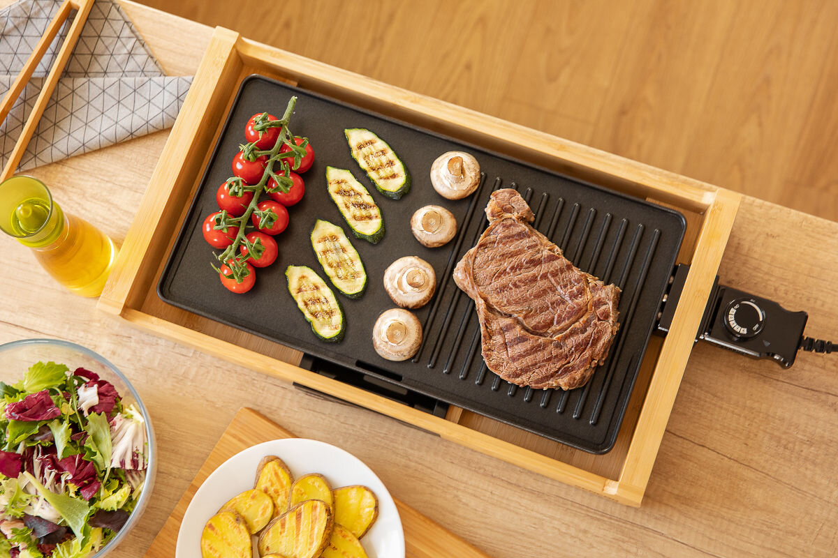 Grill elektryczny SENCOR SBG 206BK, obudowa, stylowe, akcenty, komponowanie, grill od góry stoi na blacie w kuchni, w tle potrawy na talerzach