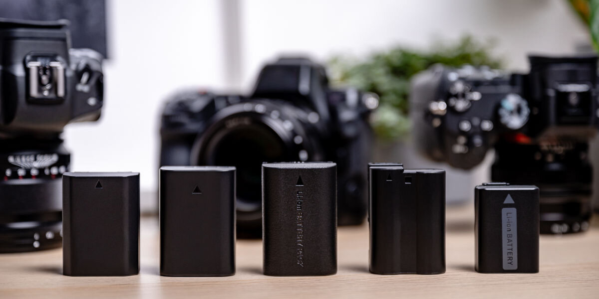 Akumulator NEWELL 11000 mAh do Canon BP-975, litowo-jonowe, pojemności, ładowanie, filmowanie, Akumulator Newell zamiennik BP-975 do Canon w otoczeniu sprzętu fotograficznego