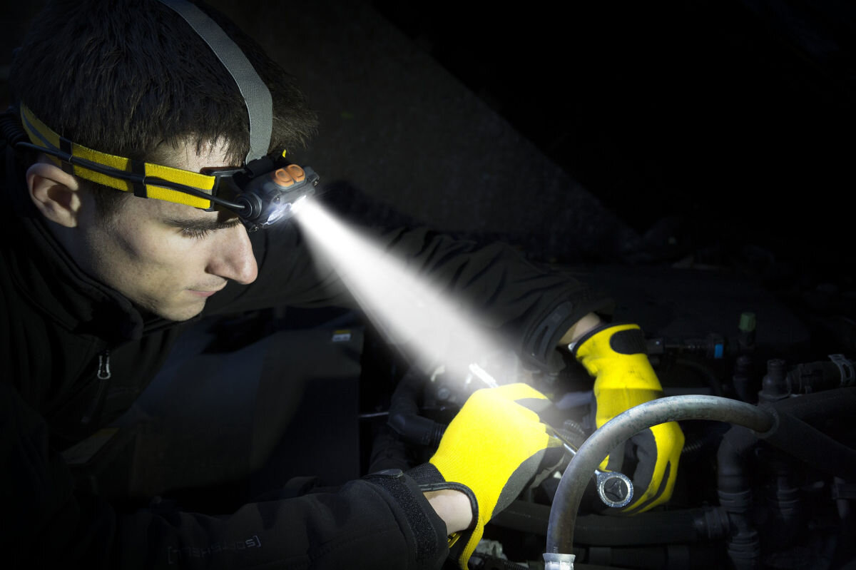 Latarka ENERGIZER Headlight Attachment, światło, oświetlanie, praca, pomoc, mężczyzna w pełnej ciemności przy pomocy latarki oświetla sobie miejsce pracy
