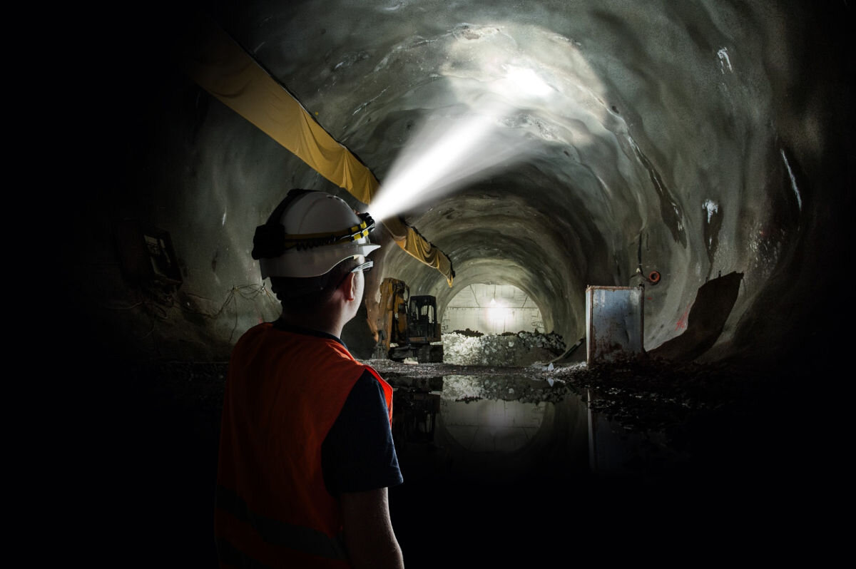 Latarka ENERGIZER Headlight Attachment, tryby, świecenie, spot, flood, power, osoba idzie ciemnym tunelem oświetlając latarką punkt na suficie tunelu