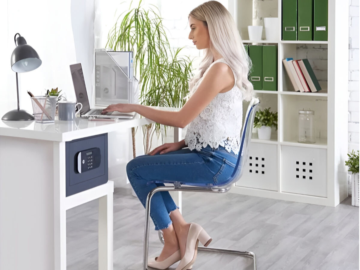 Sejf YALE YSEM 250 EG1, schowek, cenności, rzeczy, bezpieczeństwo, kobieta pracuje przy biurku, obok na półce biurka sejf