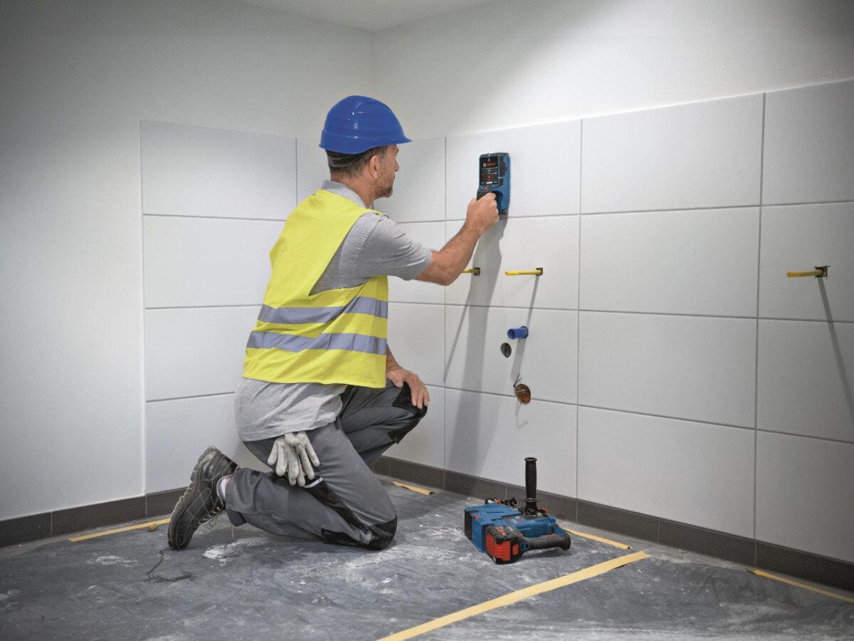 Detektor BOSCH Professional D-Tect 200 C 0601081608, ekran, menu, widok, instalacja, Pracownik używa detektora Bosch na ścianie wyłożonej kafelkami.