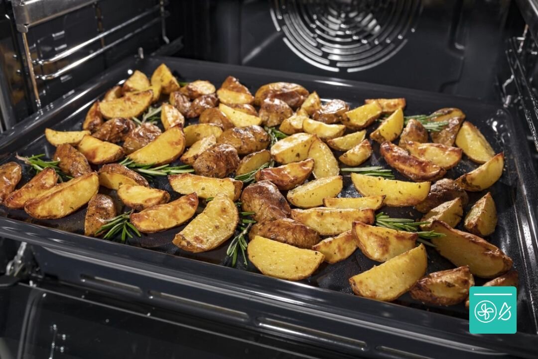 PIEKARNIK GORENJE BSA6737E15BG Perforowana blacha w piekarniku wypełniona jest rumianymi, przyprawionymi ziemniakami z dodatkiem ziół. Ujęcie podkreśla chrupiący efekt pieczenia i równomierne rozprowadzenie ciepła