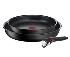 Na obrazie widoczne są dwie czarne patelnie oraz odłączany uchwyt. Patelnie mają czerwony okrągły wzór na środku dna.