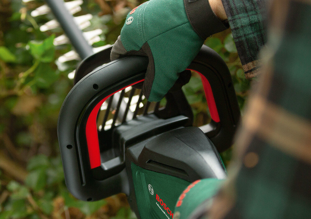 Nożyce do żywopłotu BOSCH AdvancedHedgeCut 36V-65-28 060084A301 akumulatorowe ogród zbliżenie na rękojeść osoba trzyma nożyce w dłoniach lekka i ergonomicznie zaprojektowana konstrukcja miękka powłoka antypoślizgowa włącznik na całej wewnętrznej części rękojeści ułatwia precyzyjne prowadzenie narzędzia zmniejsza zmęczenie dłoni stabilny chwyt