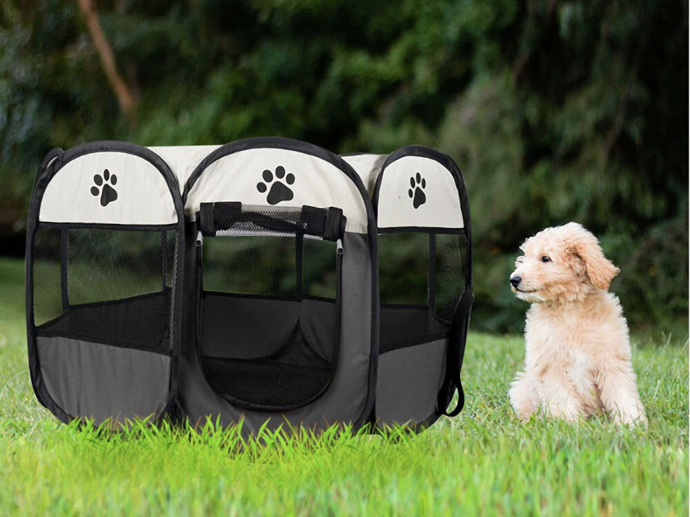 Kojec uniwersalny MUFART 15077, szary składany kojec materiałowy dla psa lub kota, bezpieczna przestrzeń w domu i na zewnątrz. Jasnobeżowy szczeniak (prawdopodobnie rasy Goldendoodle lub Labradoodle) siedzi obok rozłożonego, składanego kojca dla zwierząt. Kojec jest okrągły, w kolorach szarym i kremowym, z siatkowymi oknami i motywami czarnych psich łap. Obiekt znajduje się na trawie, z zalesionym tłem w tle.