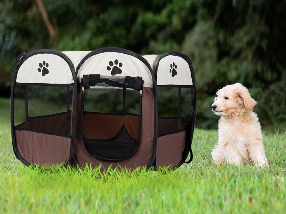 Kojec uniwersalny MUFART 15078, brązowy składany kojec materiałowy dla psa lub kota, bezpieczna przestrzeń w domu i na zewnątrz. Jasnobeżowy szczeniak (prawdopodobnie rasy Goldendoodle lub Labradoodle) siedzi obok rozłożonego, składanego kojca dla zwierząt. Kojec jest okrągły, w kolorach brązowym i kremowym, z siatkowymi oknami i motywami czarnych psich łap. Obiekt znajduje się na trawie, z zalesionym tłem w tle.