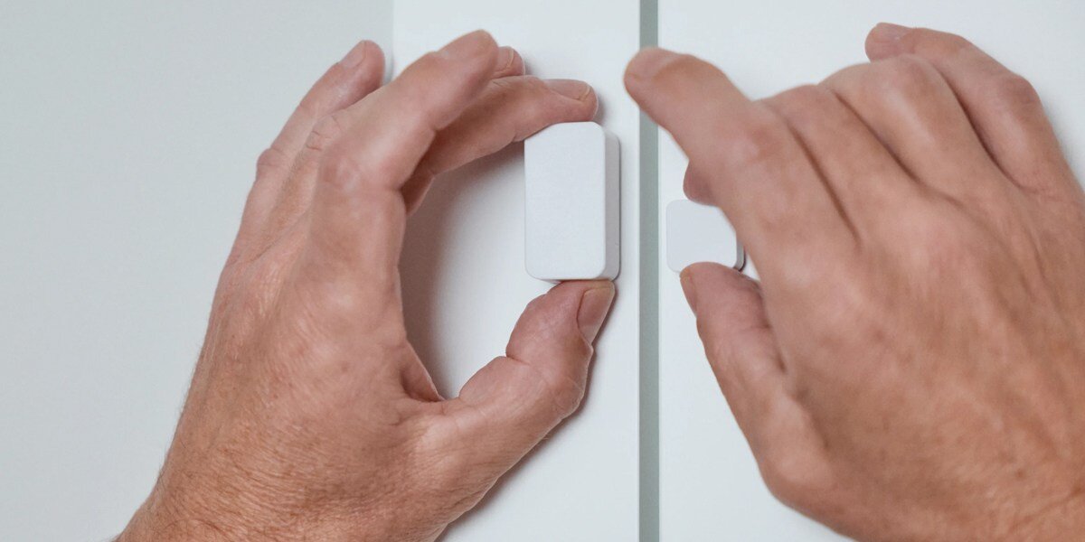 Czujnik otwarcia drzwi NUKI Door Sensor Bluetooth, położenie, wykrycie, błyskawiczne, Powiadomienia, dłonie osoby montują czujnik na drzwi