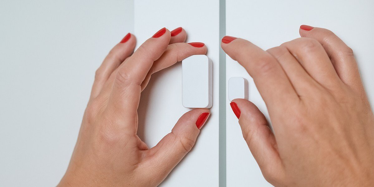 Czujnik otwarcia drzwi NUKI Door Sensor Bluetooth, intuicyjna, szybka, zamontowanie, konfiguracje, dłonie osoby montują czujnik na drzwi