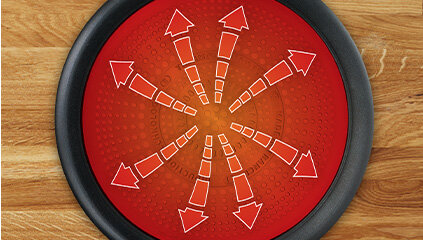 Czerwona powierzchnia z białymi strzałkami skierowanymi na zewnątrz, otoczona czarną krawędzią. Tło to drewniana powierzchnia.