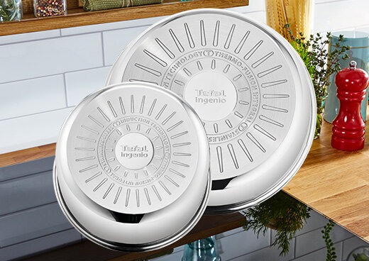 Dwie patelnie TEFAL Ingenio Emotion odwrócone dnem do góry na płycie indukcyjnej.