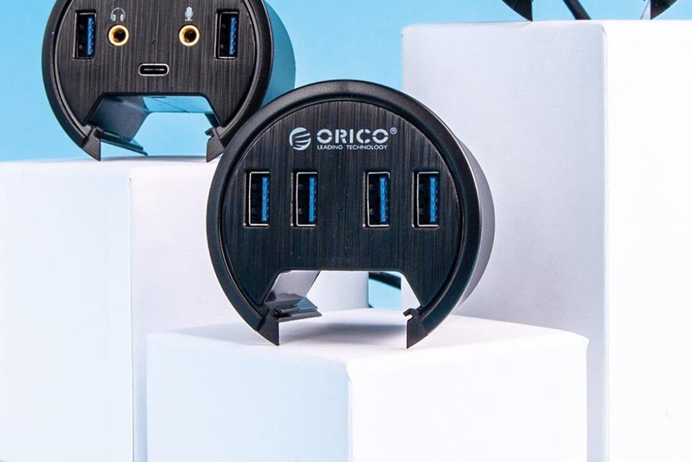 Hub ORICO DESK-4U-BK-BP Zbliżenie na czarny okrągły hub USB ustawiony pionowo, pokazujący cztery porty USB i logo producenta, porty, podłączenie, zastosowanie