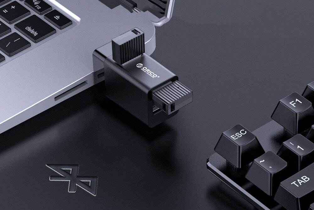 Hub ORICO Mini-U32L-BK-BP Adapter USB z trzema portami podłączony do laptopa, z dwoma pendrive'ami i klawiaturą w pobliżu, kompatybilność, obsługa