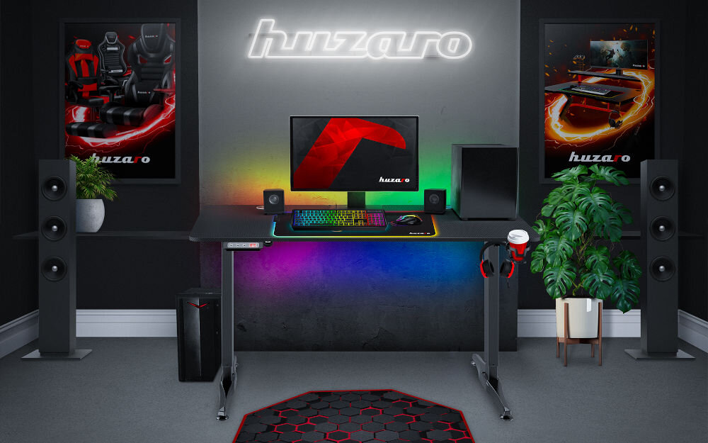 Biurko HUZARO Hero 8.5 prezentacja biurka w pokoju o ciemnych ścianach na biurku akcesoria i komputer na ścianie led z napisem huzaro i plakaty