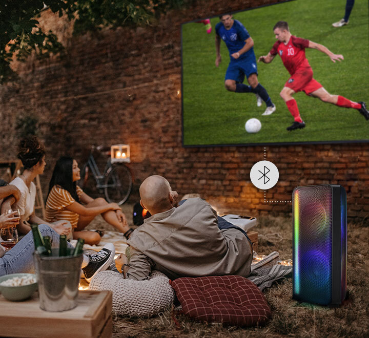 Přátelé sledují fotbalový zápas s reproduktorem Power Audio připojeným přes Bluetooth®.  MX-ST40B/EN