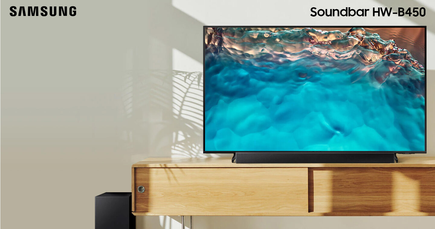 Soundbar Samsung serii B i subwoofer stojące razem z telewizorem Crystal UHD na szafce. HW-B450/EN