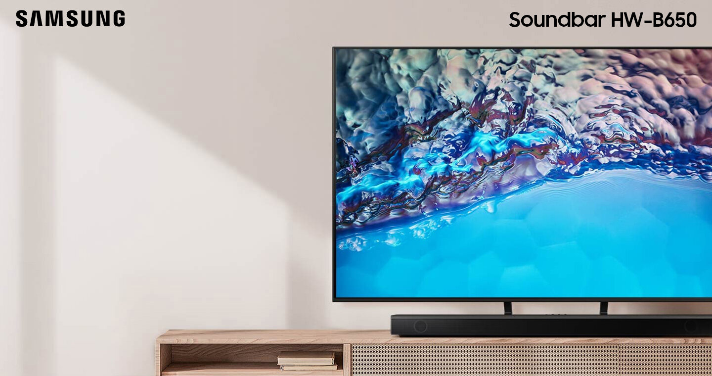 Soundbar Samsung serii B i subwoofer stojące razem z telewizorem Crystal UHD na szafce. HW-B650/EN