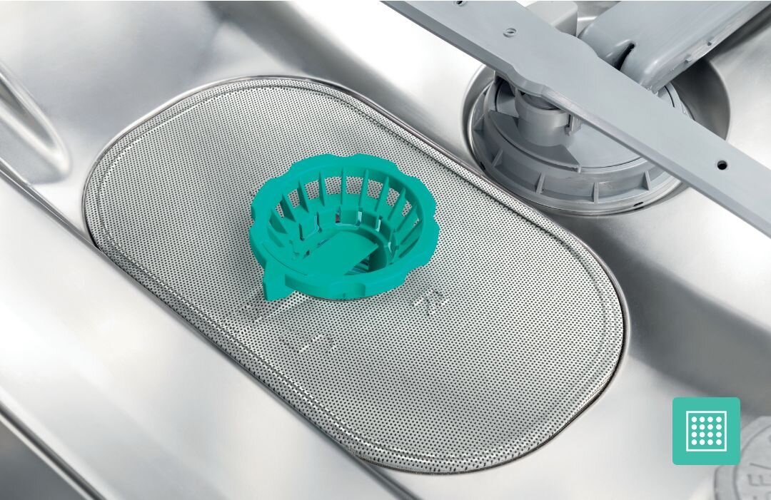 ZMYWARKA GORENJE GV520E15 Wnętrze zmywarki z metalowym filtrem na dnie, na którym umieszczono turkusowy koszyczek na resztki, obok widoczno jest ramię spryskujące, co pokazuje system filtracji i ochrony przed zanieczyszczeniami