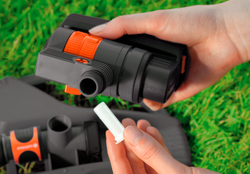 Zraszacz wahadłowy GARDENA Aquazoom Compact trawnik osoba trzyma w dłoni zraszacz i filtr filtr zatrzymujący zabrudzenia wyjąć go i przepłukać pod bieżącą wodą chroni dysze przed zanieczyszczeniami stabilne i równomierne podlewanie