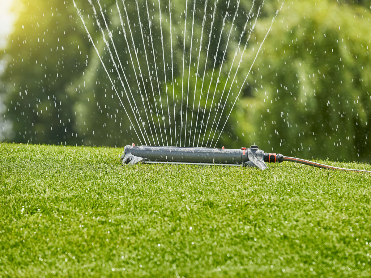 Zraszacz GARDENA Aquazoom L, właściwości, materiały, wykonanie, inwestycja, w tle ogród, na pierwszym planie zraszacz podlewa trawnik