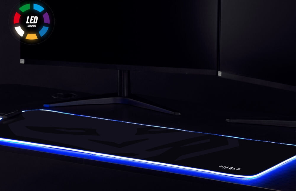 Podkładka DIABLO CHAIRS LED 1127 prezentacja podkładki na ciemnym biurku z podświetleniem w kolorze niebieskim na biurku monitory w rogu znaczek z kolorami LED podświetlenie RGB 10 trybów 7 kolorów dostosuj atmosferę