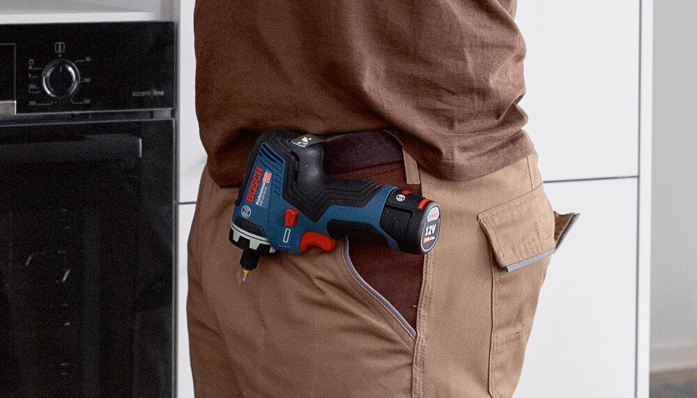 Wiertarko-wkrętarka BOSCH Professional GSR 12V-35 FC 06019H3000 pomieszczenie zbliżenie na pas osoby osoba na pasku ma przymocowaną wiertarko-wkrętarkę wspiera codzienne prace montażowe, serwisowe i budowlane wiercenie otworów w drewnie i stali szybkie wkręcanie śrub bez użycia kilku narzędzi oszczędzasz czas miejsce w skrzynce i energię