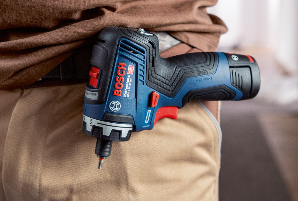 Wiertarko-wkrętarka BOSCH Professional GSR 12V-35 FC 06019H3000 pomieszczenie zbliżenie na pas osoby osoba na pasku ma przymocowaną wiertarko-wkrętarkę metalowy zaczep zawiesić na pasku, narzędziowym pasie roboczym lub drabinie ogranicza się konieczność odkładania urządzenia na powierzchnię zwiększa komfort i tempo pracy