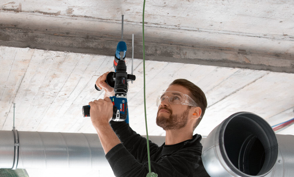 Wiertarko-wkrętarka BOSCH Professional GSR 12V-35 FC 06019H3000 hala betonowy sufit osoba wierci otwór w suficie szeroki zakres mocowania 0,8–10 mm radzi sobie z otworami do 32 mm w drewnie 10 mm w stali funkcja Autolock przyspiesza wymianę osprzętu
