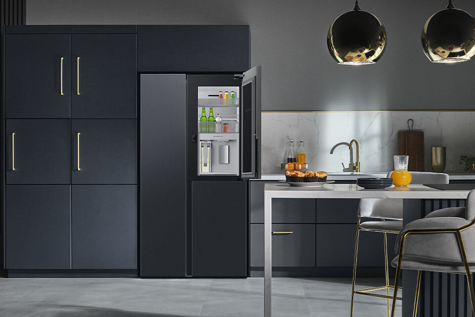 Zdjęcie pokazujące lodówkę Samsung z centrum napojów stojącą w przestronnej i nowocześnie urządzonej kuchni
