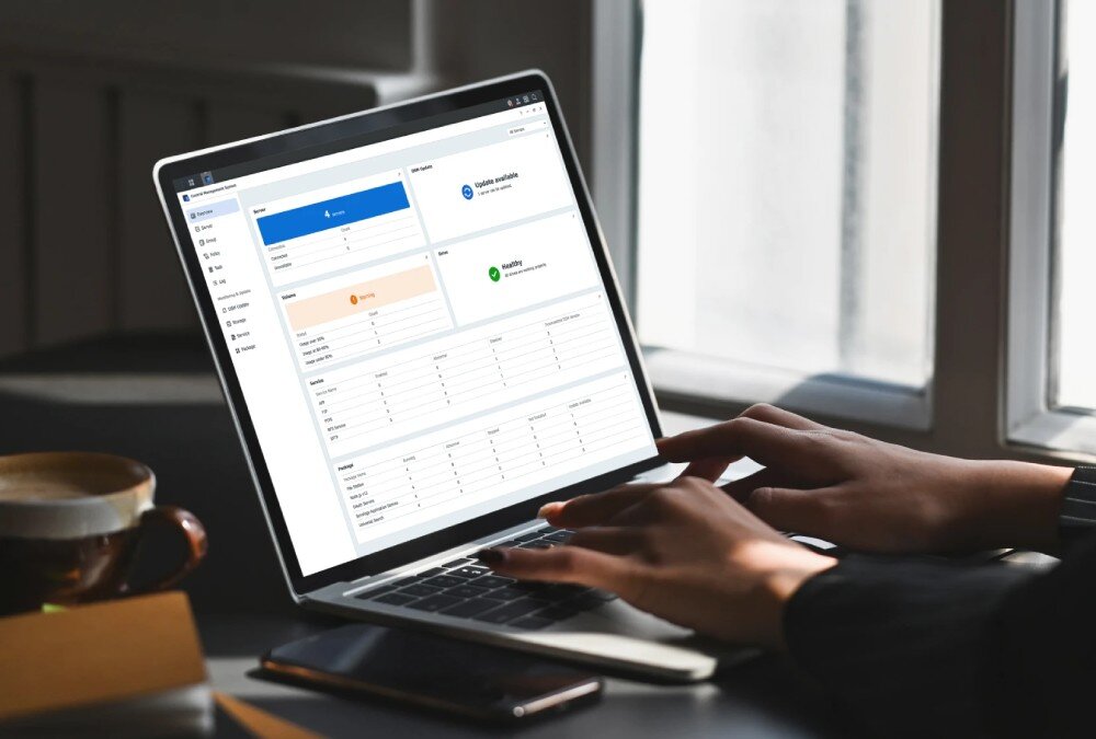 Serwer plików SYNOLOGY RS422+ Dłonie piszące na klawiaturze laptopa, na którego ekranie wyświetla się panel administracyjny systemu operacyjnego z wykresami stanu serwerów, system, funkcje